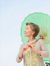 Portrait of senior woman holding green parasol.