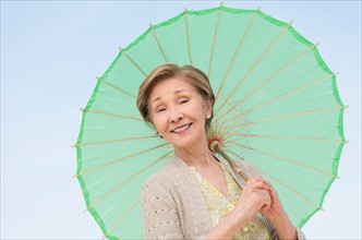 Portrait of senior woman holding green parasol.