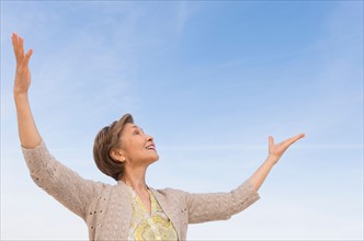 Senior woman looking up at blue sky.