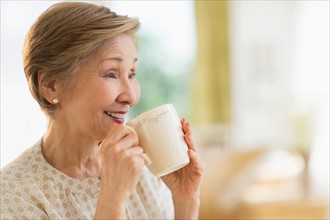 Senior woman drinking from mug.