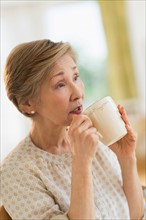 Senior woman drinking from mug.