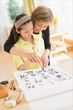 Grandmother and granddaughter (8-9) painting japanese symbols.