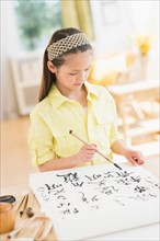 Girl (8-9) painting japanese symbols.