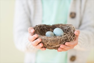 Girl (8-9) holding bird's nest with eggs.