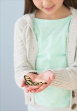 Girl (8-9) holding butterfly.