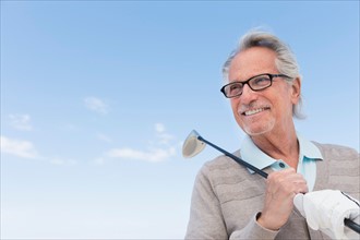 Senior man holding golf club.