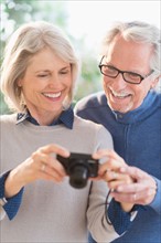 Smiling senior couple with digital camera.