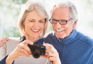Smiling senior couple with digital camera.