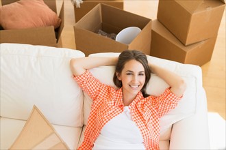 Young woman resting on sofa after moving into new home.