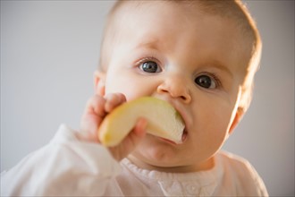 Portrait of baby girl (6-11 months) eating apple