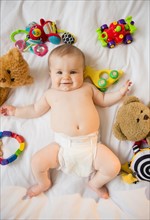 Portrait of baby girl (6-11 months) lying down among toys