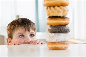 Portrait of boy (4-5) looking at stacked donuts