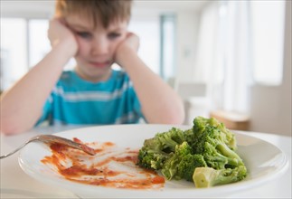 Portrait of boy (4-5) annoyed to eat broccoli