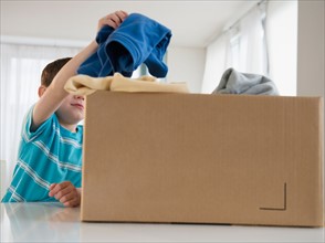 Boy (4-5) putting clothing into box