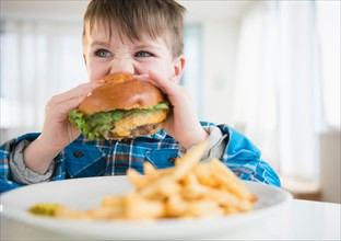 Portrait of boy (4-5) eating hamburger