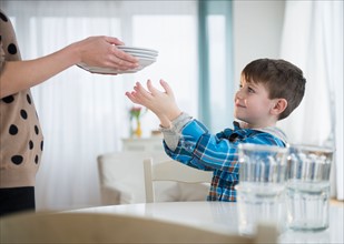 Boy (4-5) helping mother to set table