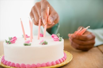 Close up of woman's hands putting candles on birthday cake