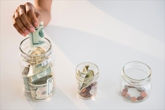 Close up of woman's hand putting money into jar