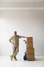 Portrait of delivery man standing next to push cart
