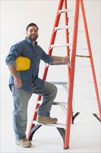 Portrait of construction worker standing by ladder