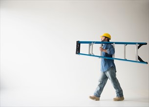 Side view of man carrying ladder