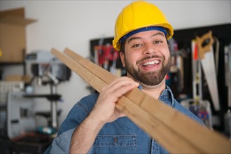 Portrait of smiling worker, holding boards on his shoulder