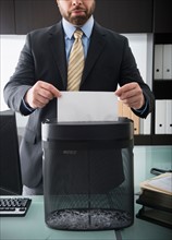 Portrait of man putting paper into paper shredder