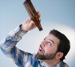 Portrait of man holding empty beer bottle and looking into it