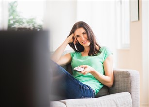 Portrait of woman watching TV on sofa
