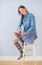 Studio Shot of woman sitting on stool wearing striped kneesocks