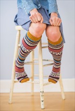 Studio Shot, Low section of woman sitting on stool wearing striped kneesocks