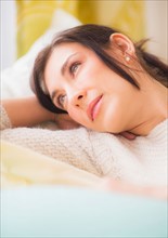 Woman lying on bed with hand behind head