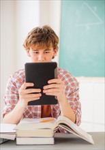 Teenage boy (14-15) sitting in classroom with tablet pc