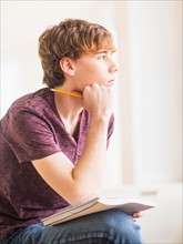 Teenage boy (14-15) sitting and holding pencil and note pad
