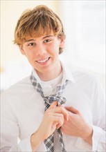 Teenage boy (14-15) adjusting tie