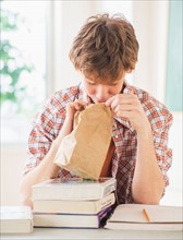 Teenage boy (14-15) looking inside paper bag