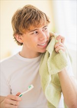 Teenage boy (14-15) with toothbrush and towel