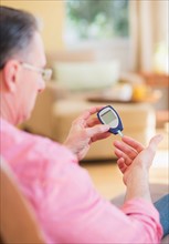Diabetic man using glucose blood meter