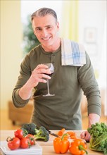 Portrait of man in kitchen, holding wine glass