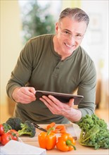 Portrait of man in kitchen, holding digital tablet