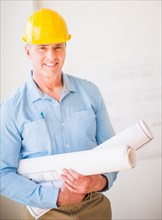 Portrait of man in hardhat holding rolled up blueprints