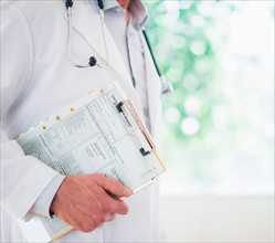 Mid section of doctor holding medical record
