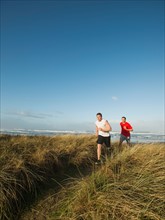 Young adult men running on dune