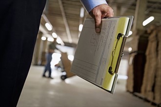 Close up of man holding clipboard in warehouse