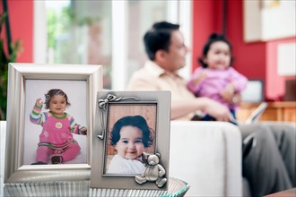 Father and kid (6-11 months) and portraits in frames in foreground