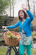 Mature woman with fresh vegetables in bike basket
