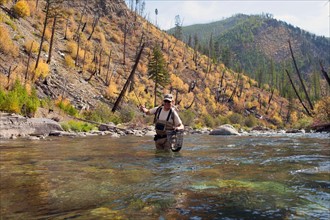 Fisherman wading in river
