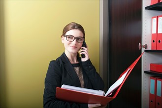 Businesswoman reading files and talking on cell phone