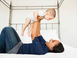 Mother lifting her son (2-5 month), playing happily