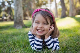 Portrait of smiling girl (4-5 years) lying on grass in park